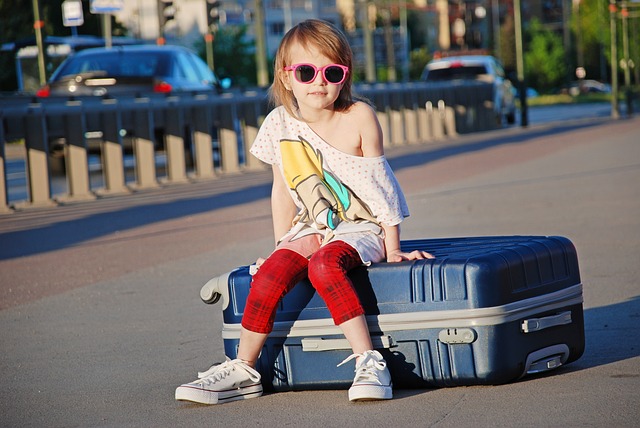 Flicka sitter på en resväska